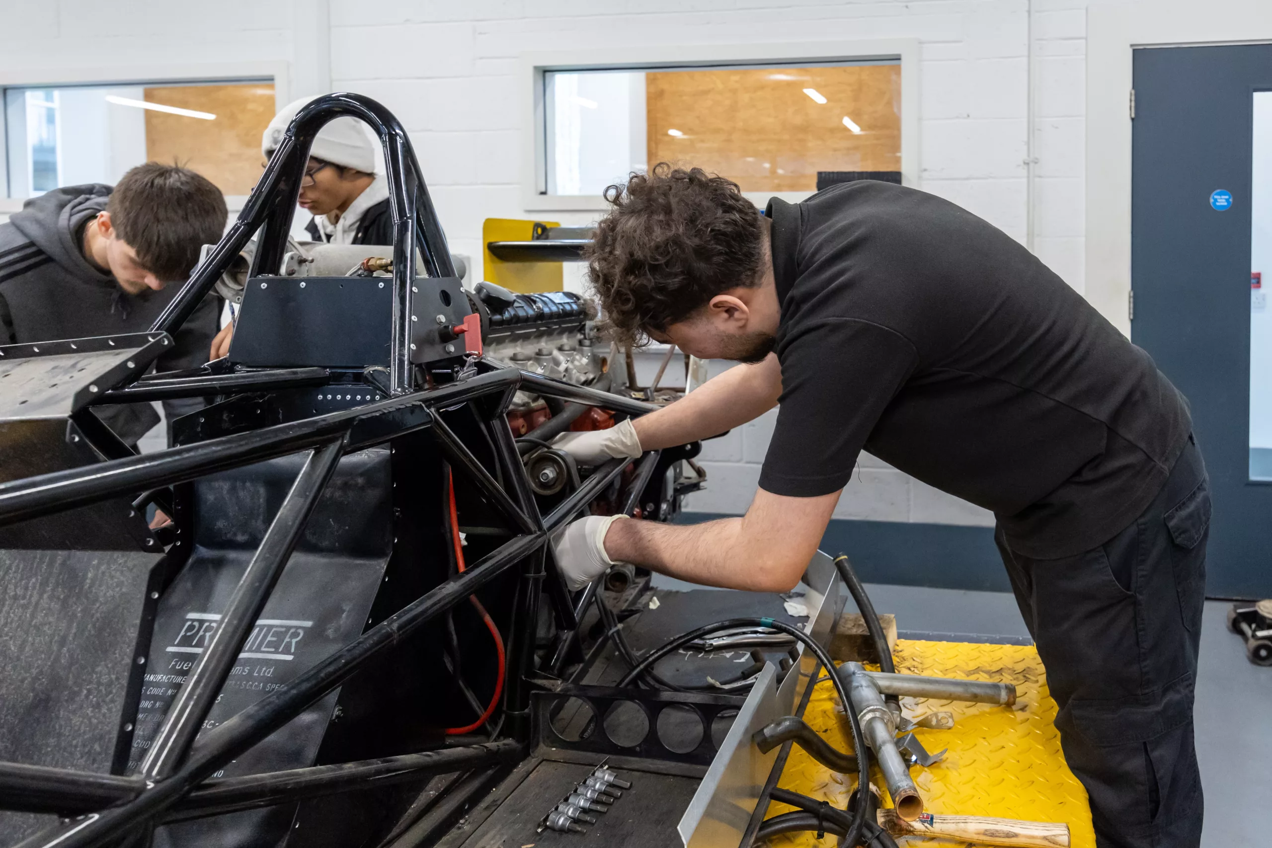 Engineering student assembling a race car structure – A hands-on mechanical engineering project in progress.
