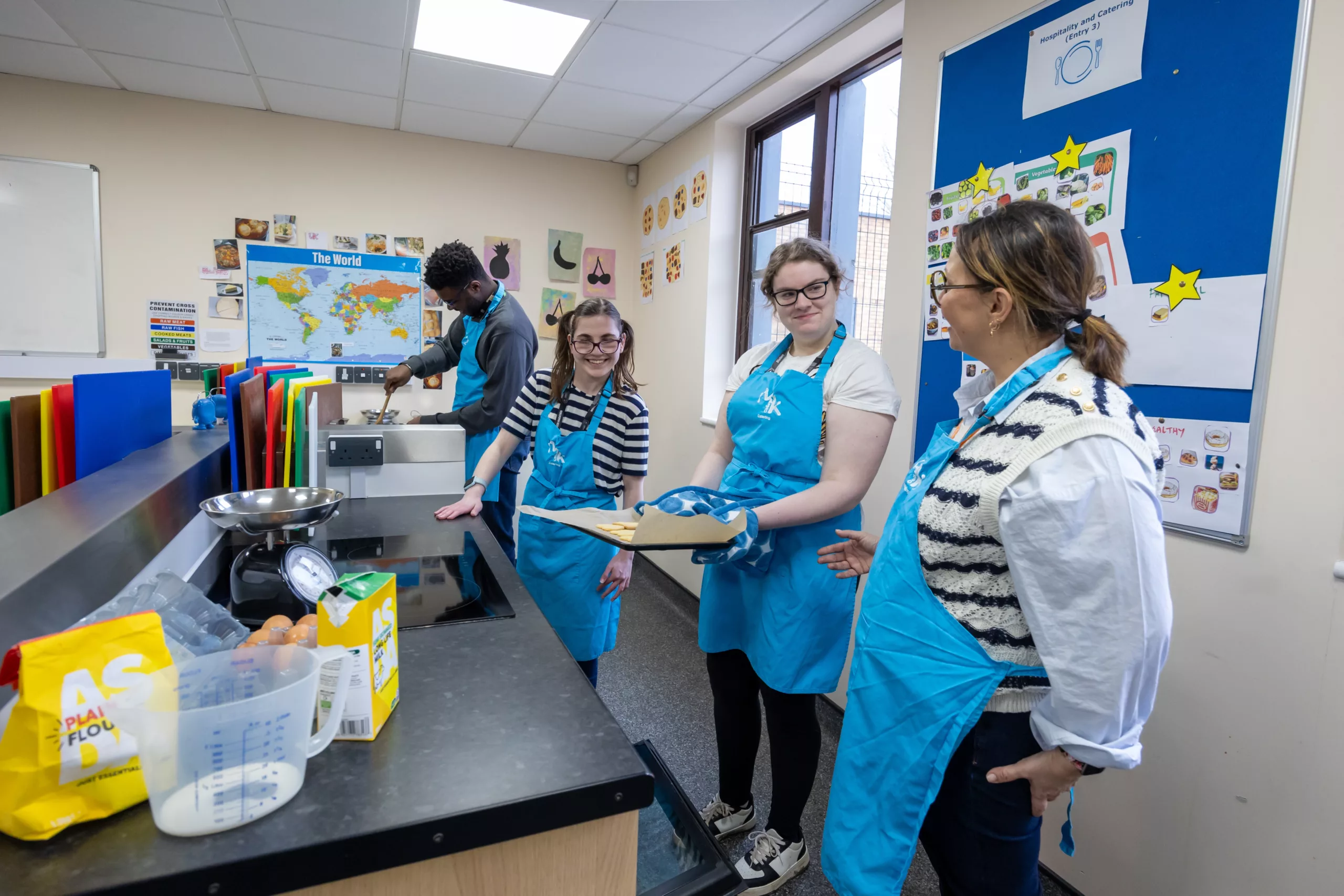 Students wearing an apron, standing behind a counter in a catering class