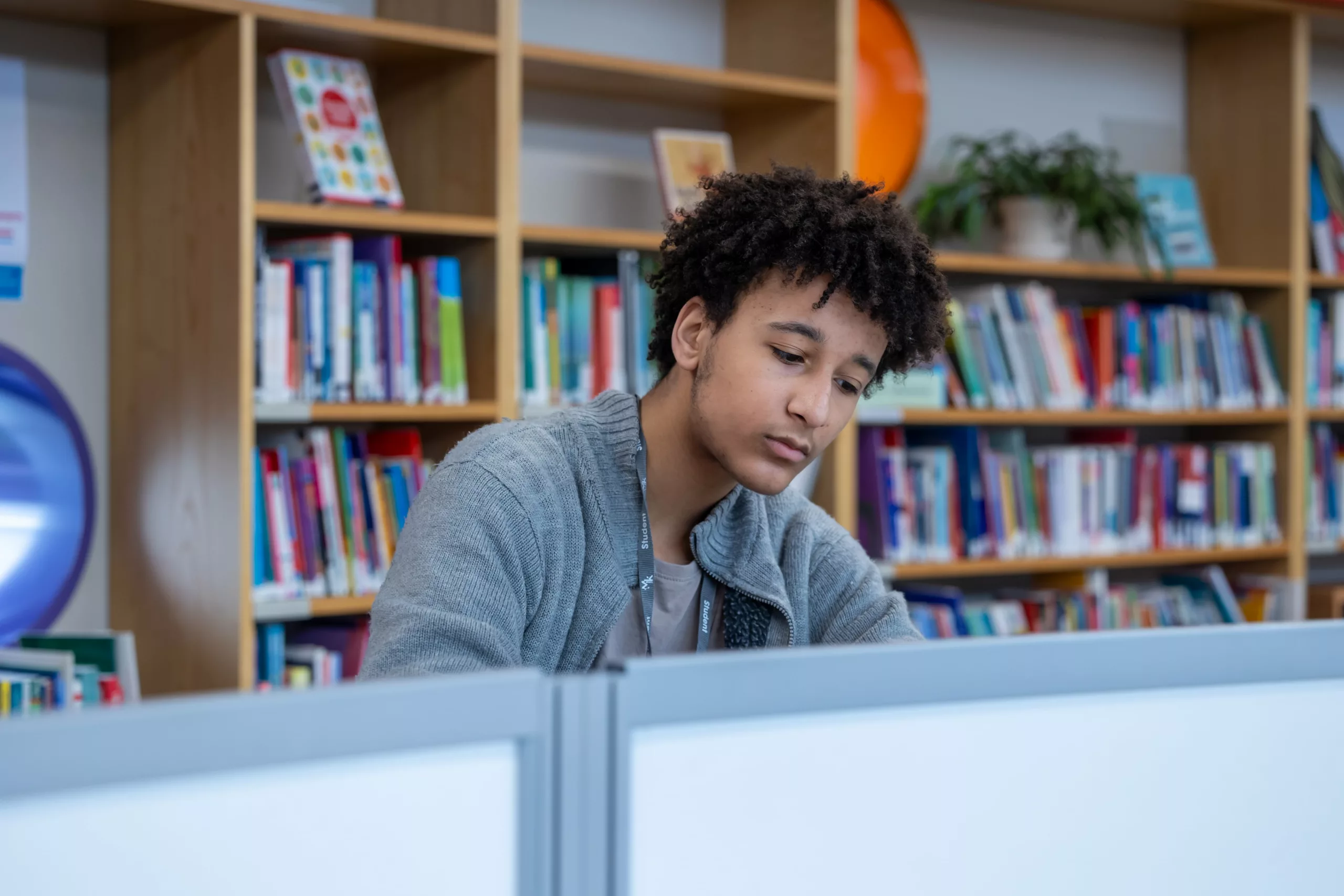 Male student working on a laptop in a modern workspace – A young man smiling while studying.