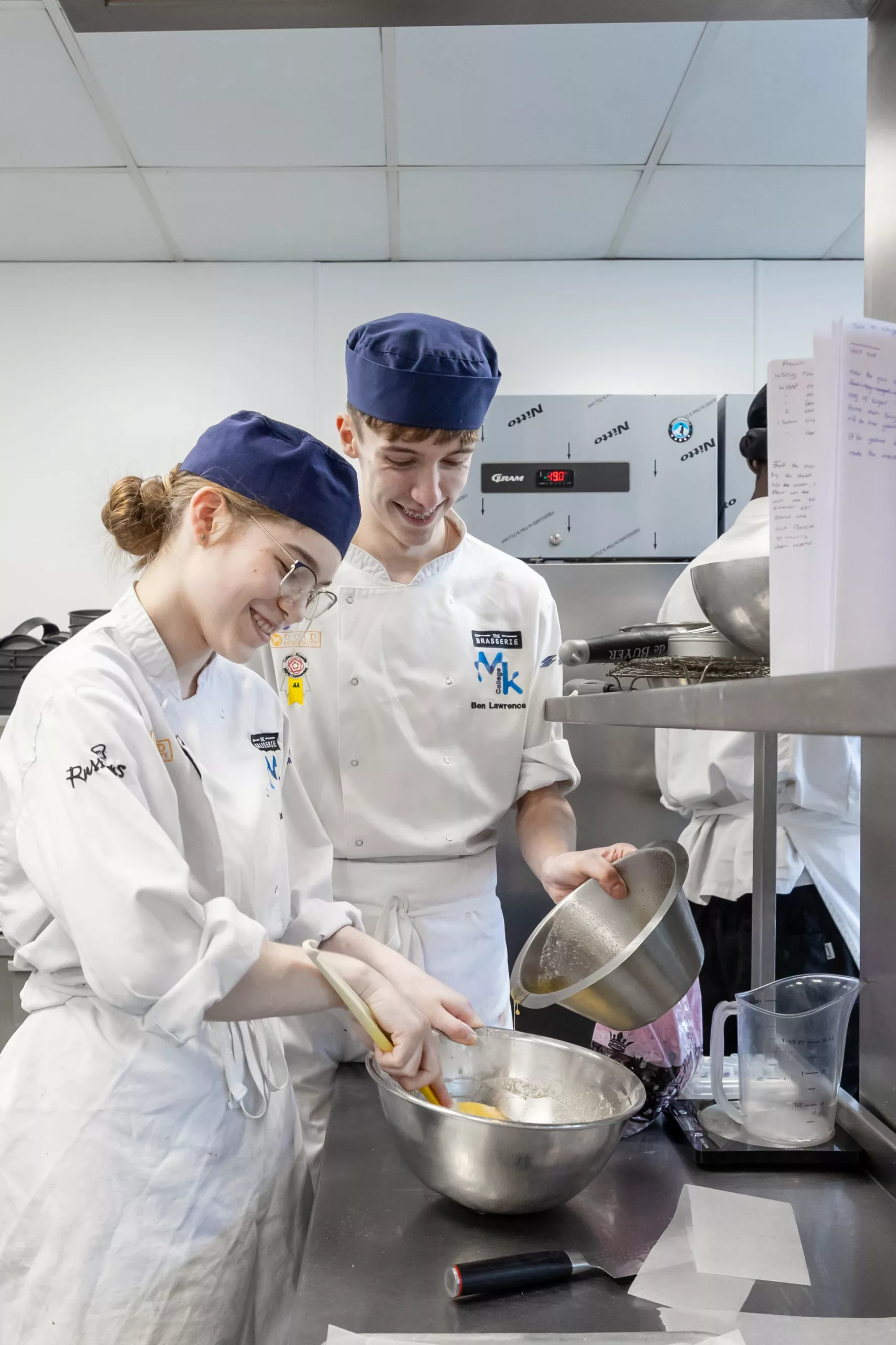 Hospitality students working in a professional kitchen – Young chefs preparing food as part of their college training.