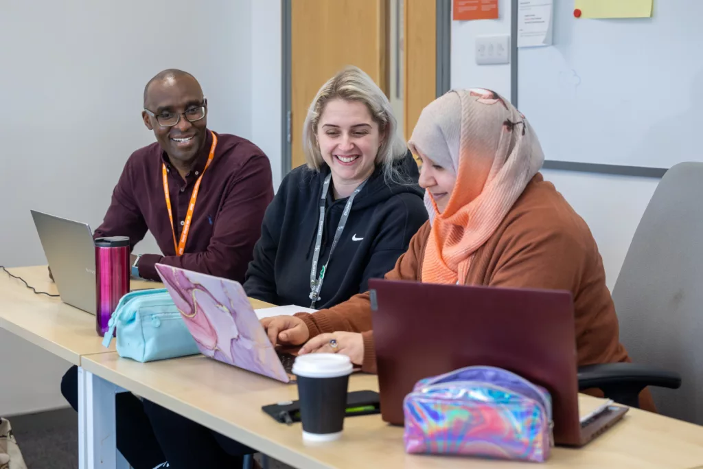 A group of students working together in a classroom on laptops