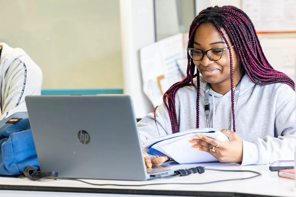 A young female MK College student, readying though a text book in a science lab.