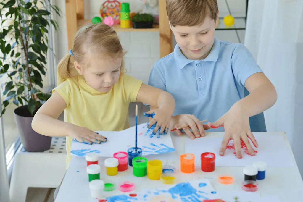 Two children playing with colourful fingerpaints.