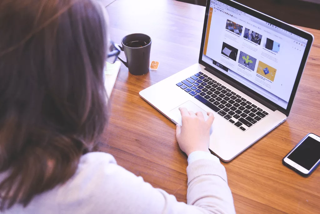 A photograph of an anonymous woman looking at her computer.