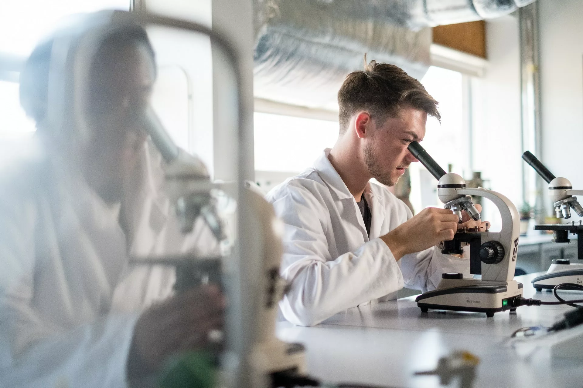 Science students sat at a bench using a microscope