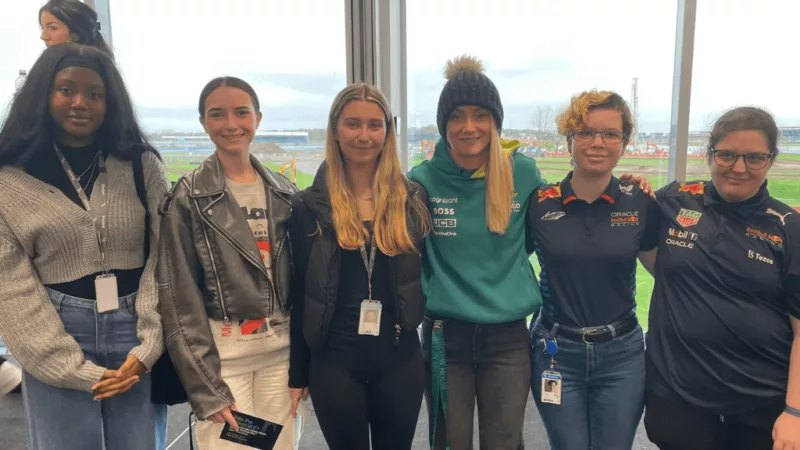 College students and staff posing together – A group of young professionals and educators posing for a photo in a modern setting.