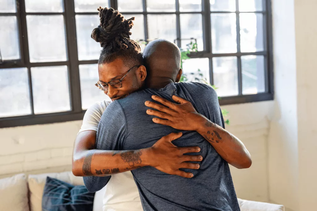 Two men hugging in a bright room.