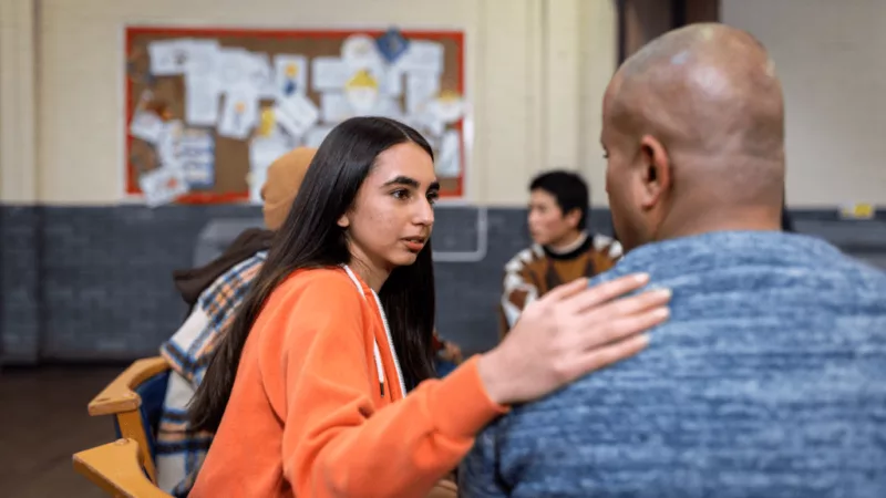 A woman placing her hand on a man's shoulder, as a sign of compassion.